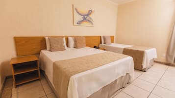 A hotel room with two beds, a wooden headboard, a nightstand, and a painting on the wall.