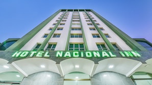 Exterior del Hotel Nacional Inn con un diseño moderno, destacando un cartel llamativo y amplias ventanas.