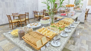 Montaje de bufé con diversos alimentos, como pan, pasteles y un pastel, sobre un mostrador de mármol.