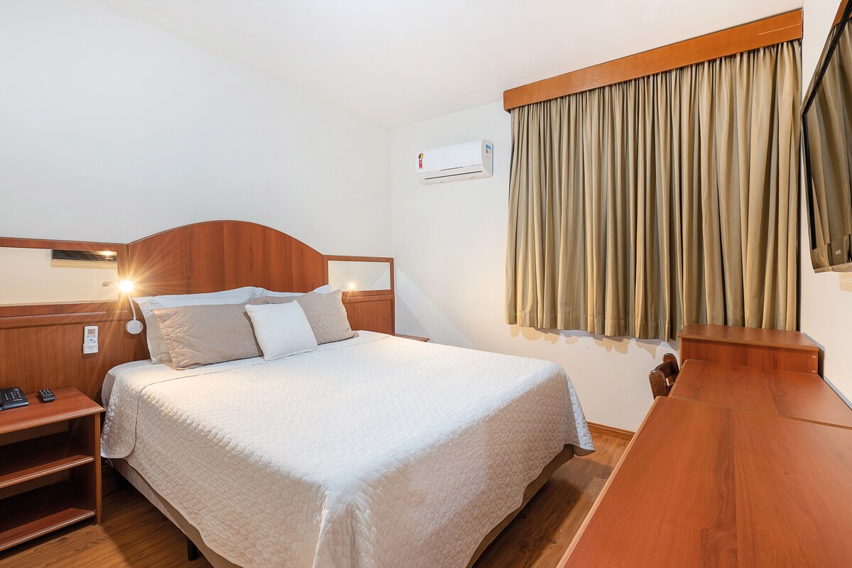Una habitación de hotel con cama, mesita de noche y escritorio.
