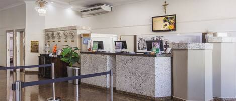 A reception area with a marble counter, a cross on the wall, and a chandelier.