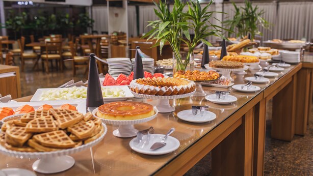 A buffet with various food items and a plant centerpiece. - Hotel Nacional Inn Ribeirão Preto (Ribeirão Preto)