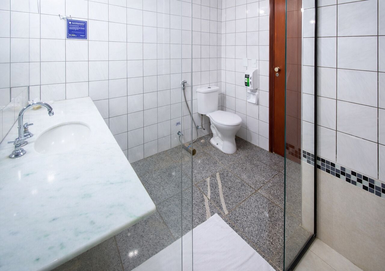 Ett badrum med en handfat av marmor, en toalett och en duschkabin med glasväggar.