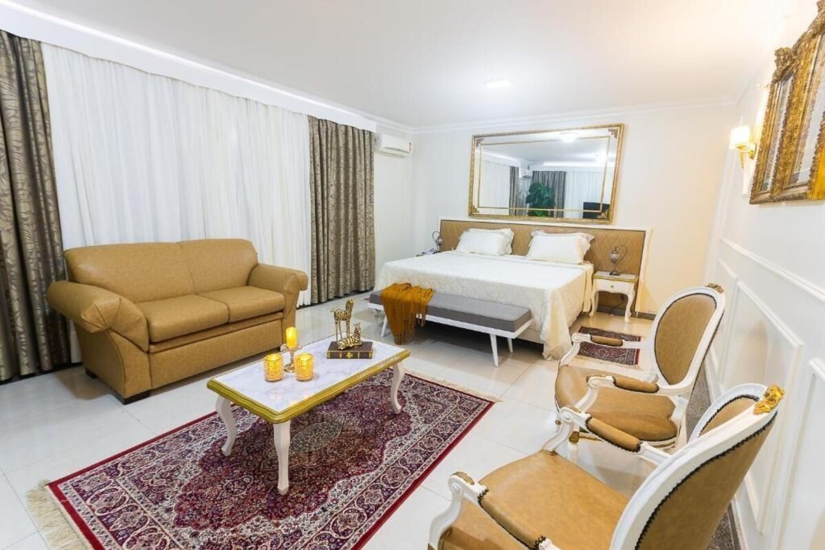 A hotel room with a bed, a sofa, a coffee table, and a chair.