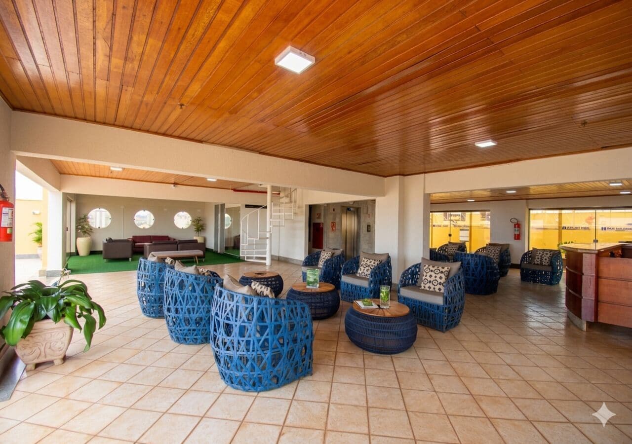 A spacious lobby with wooden ceiling, blue woven seating, and a green carpeted area.
