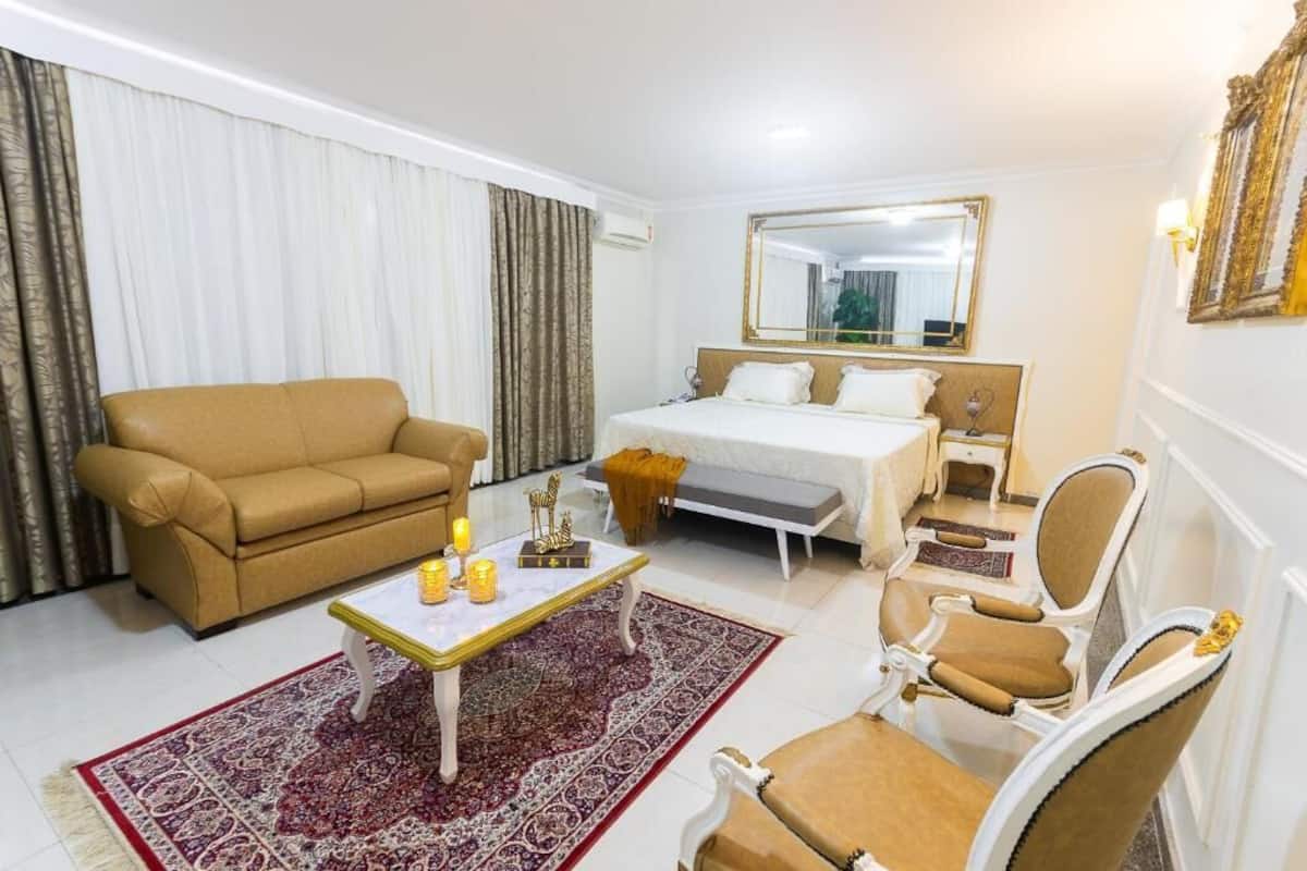 Ein Hotelzimmer mit einem Bett, einer Couch, einem Sessel, einem Couchtisch und einem großen Spiegel.
