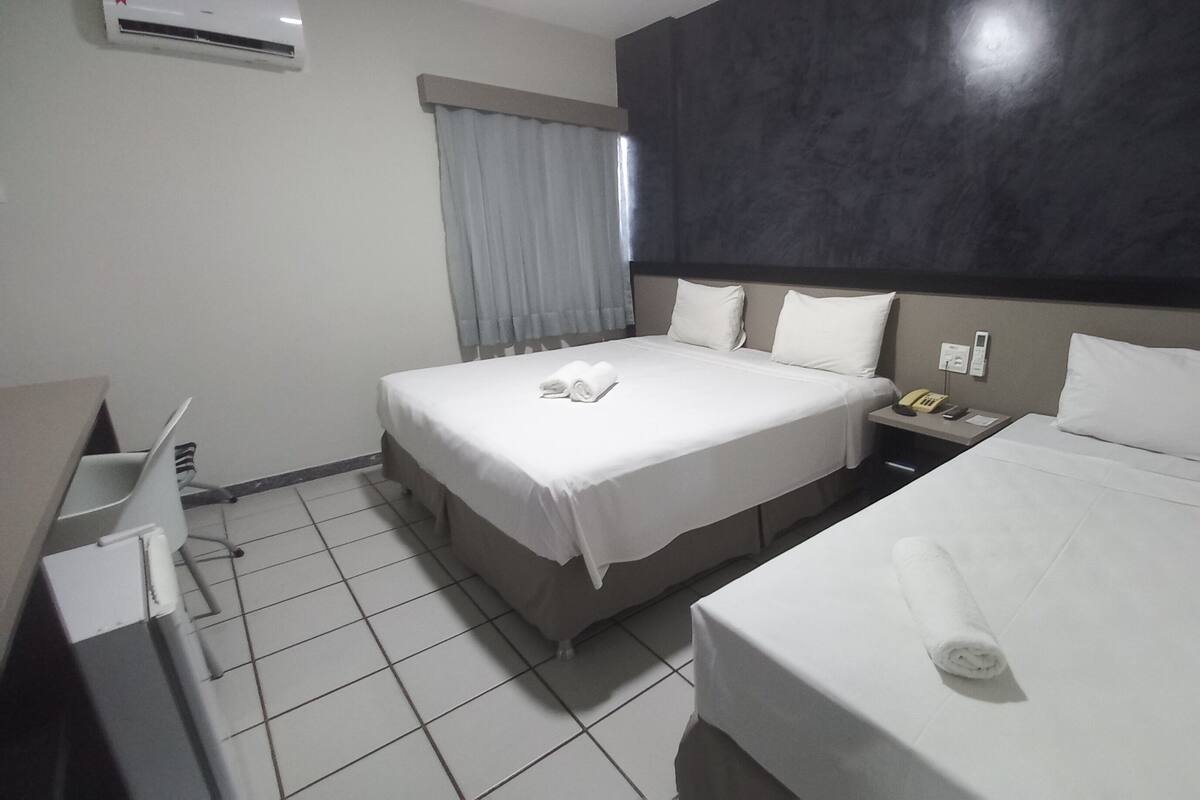 A hotel room with two beds, a desk, and a telephone.