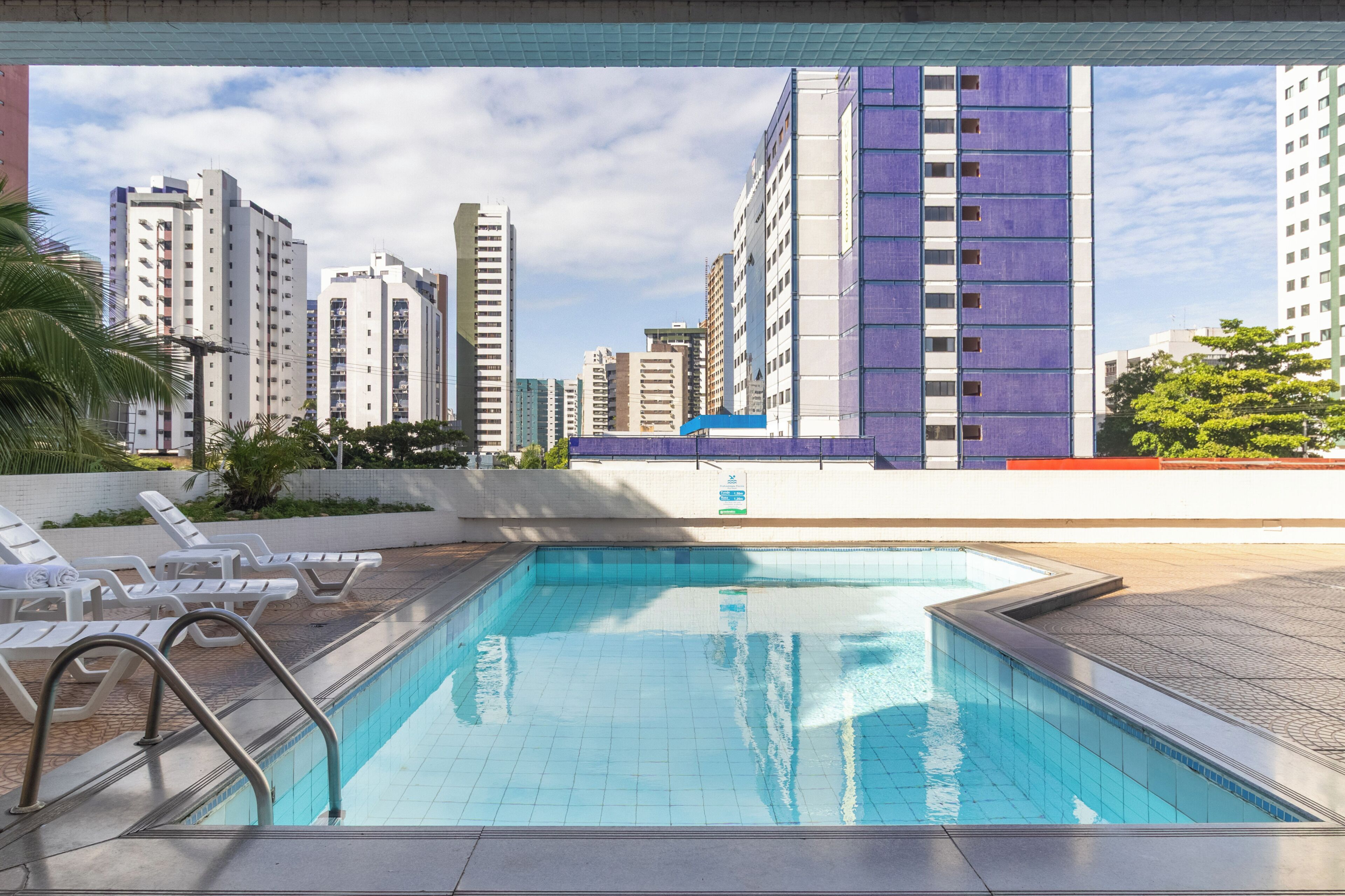 Una piscina al aire libre, sombrillas, sillones reclinables de piscina