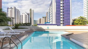 Una piscina al aire libre, sombrillas, sillones reclinables de piscina