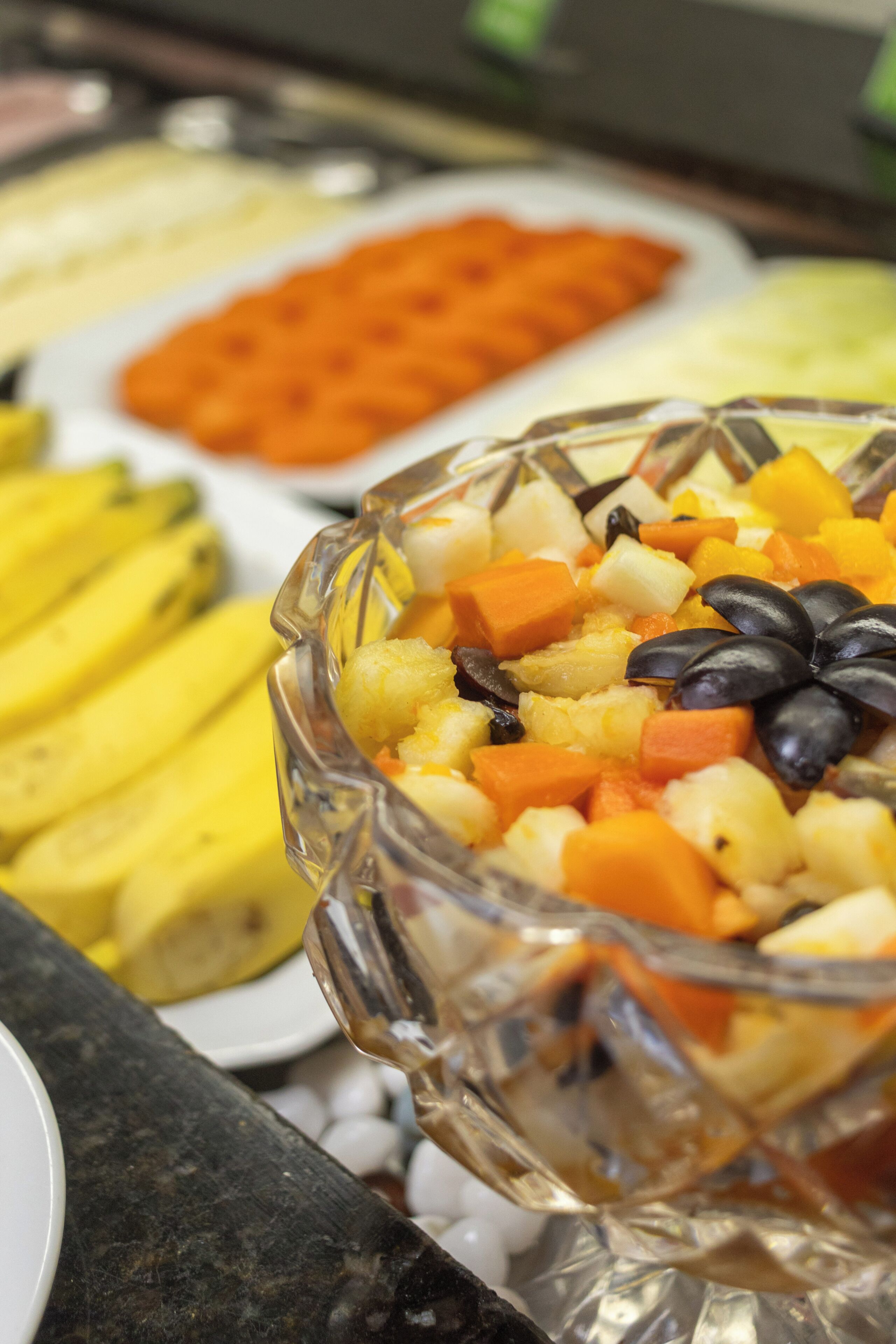 A buffet with various dishes including fruits and vegetables.