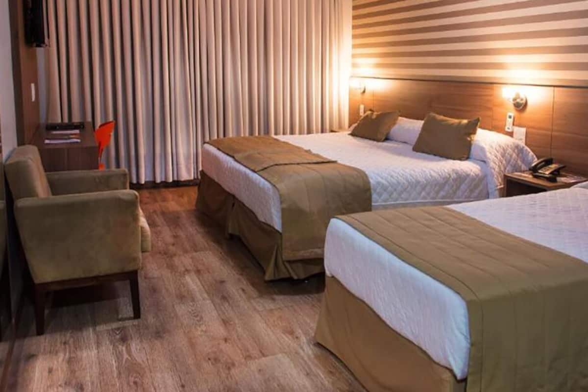 Une chambre d’hôtel avec deux lits, un bureau et une chaise.