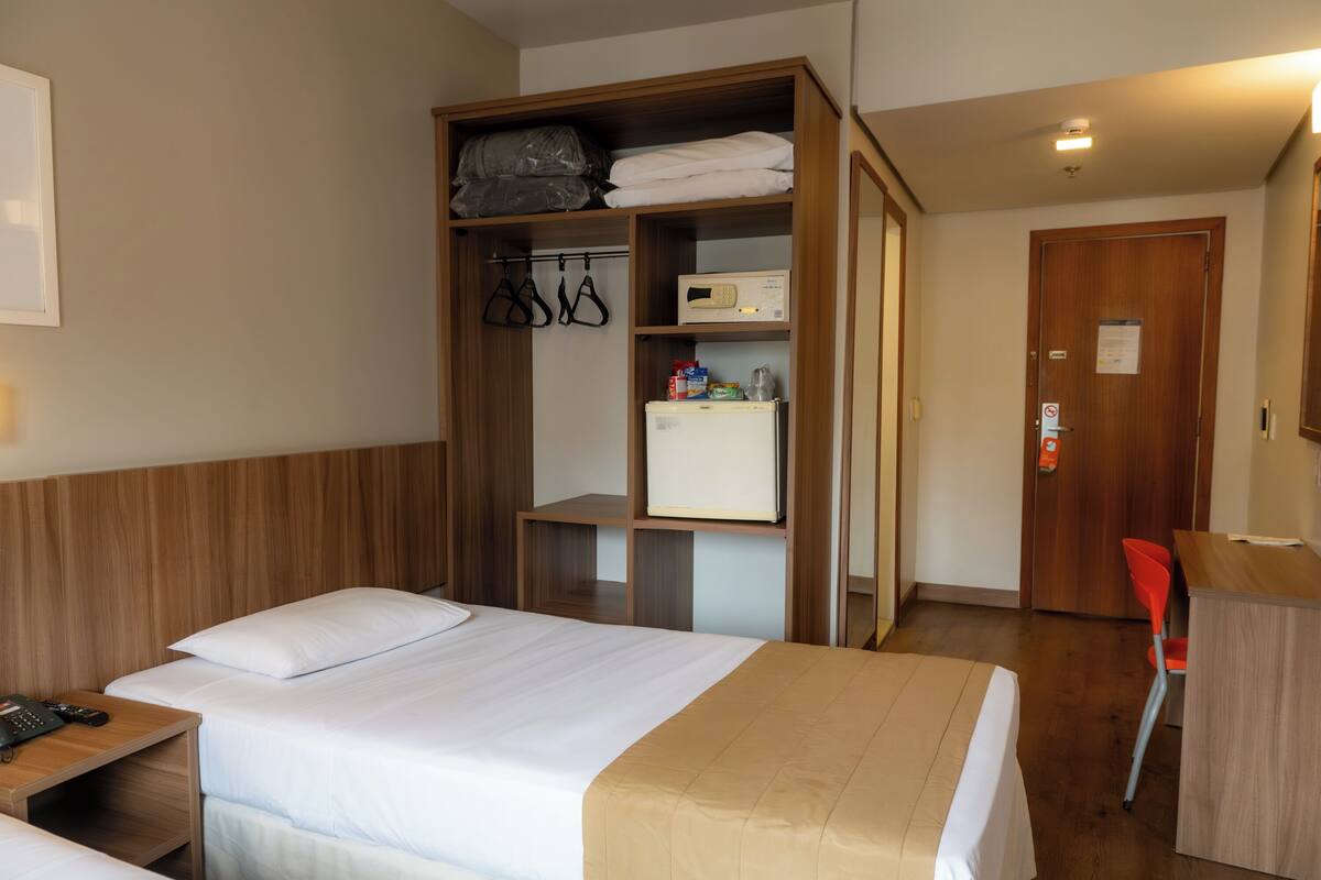 Une chambre d’hôtel avec un lit, une armoire, un bureau et une chaise.