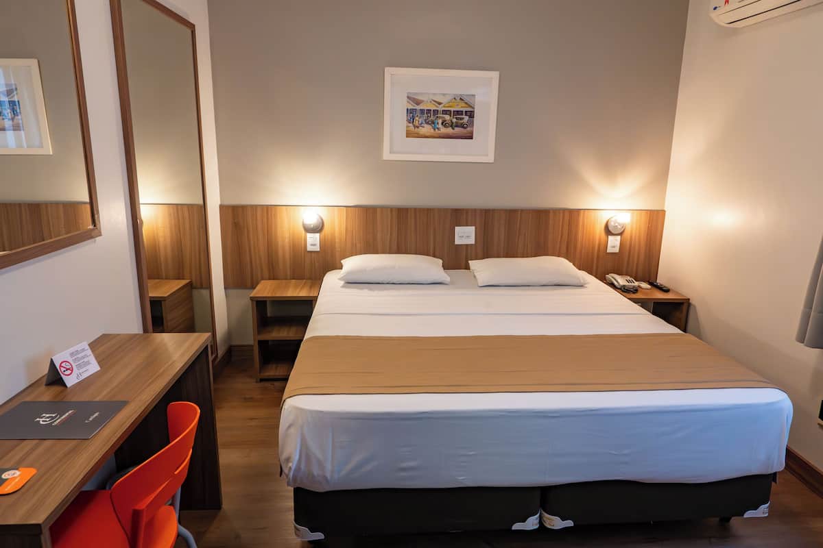 Une chambre d’hôtel comprenant un lit, des tables de chevet, un bureau et une chaise.