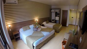 Habitación de hotel con una cama grande, una cama individual, un escritorio con silla, televisor y minibar.