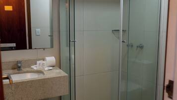 Een moderne badkamer met een douche met glazen wand, een wastafel met aanrechtblad en een spiegel erboven.