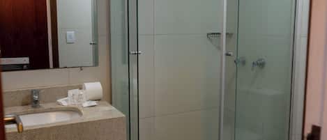 A modern bathroom with a glass-enclosed shower, a sink with a countertop, and a mirror above the sink.