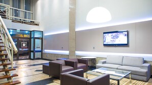 Eine moderne Lobby mit Treppe, Sitzbereich und einem Fernsehbildschirm.