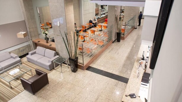 Eine moderne Hotelhalle mit Sitzgelegenheit, einer Rezeption und einer Glastrennwand.