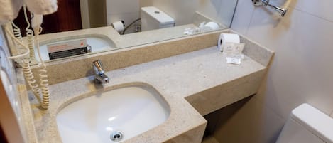 Une salle de bain équipée d’un lavabo, d’un miroir, d’un porte-serviettes et de toilettes.