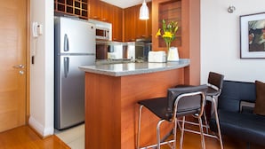 A compact kitchen with a refrigerator, microwave, and a small bar area with stools. - Apart Hotel Cambiaso (Santiago)
