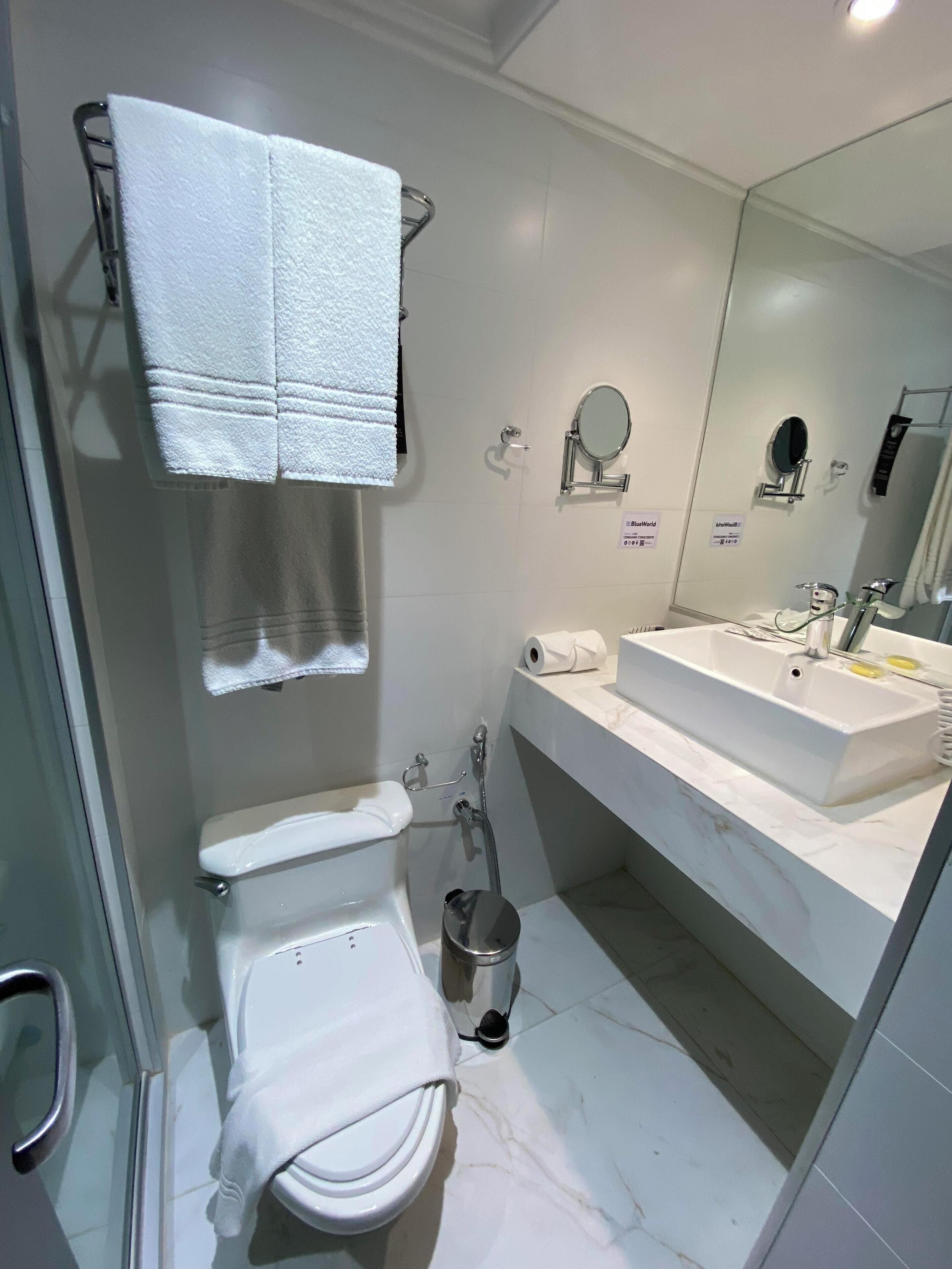 A modern bathroom with a toilet, bidet, sink, and a mirror.