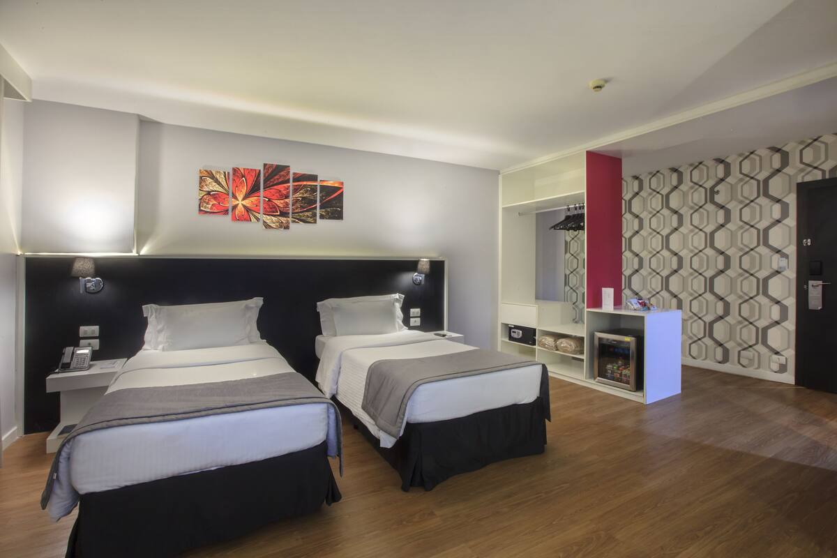 Une chambre d’hôtel avec deux lits, un bureau, un téléphone et un mini-bar.