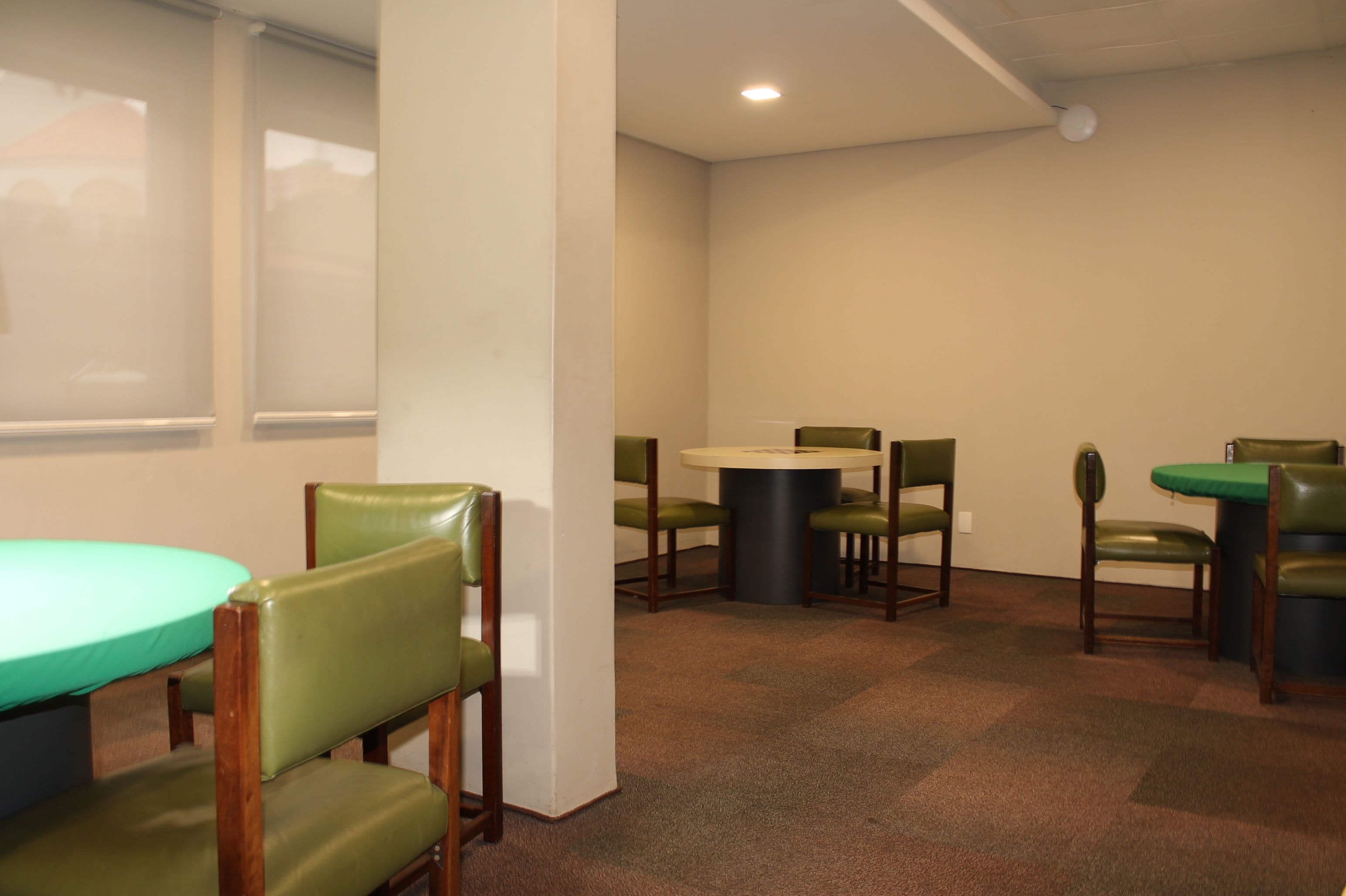 A conference room with a round table, green chairs, and a carpeted floor.