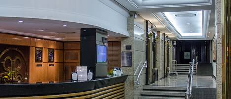 A lobby with a reception desk, a large chandelier, and a star-patterned floor.