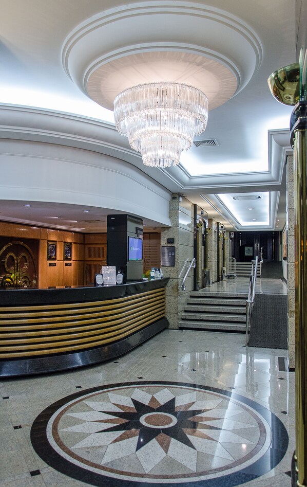 A lobby with a reception desk, a large chandelier, and a star-patterned floor.