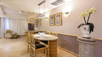 A dining area with a round table, chairs, a vase with flowers, and framed pictures on the wall.