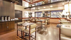 Un interior de restaurante moderno con techos altos, pisos de madera y una combinación de asientos tipo cabina y mesas.