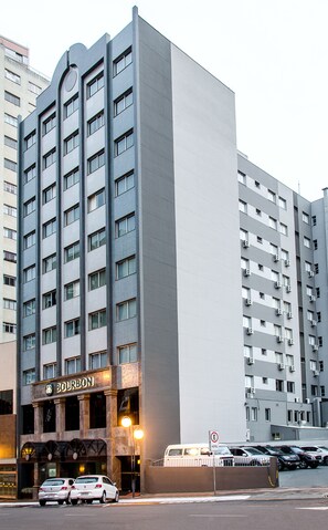 A multi-story hotel with a prominent Bourbon sign at the entrance, featuring a modern architectural design with a mix of brick and smooth surfaces.