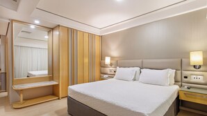 Habitación de hotel con una cama grande, mesitas de noche, un espejo y un armario.