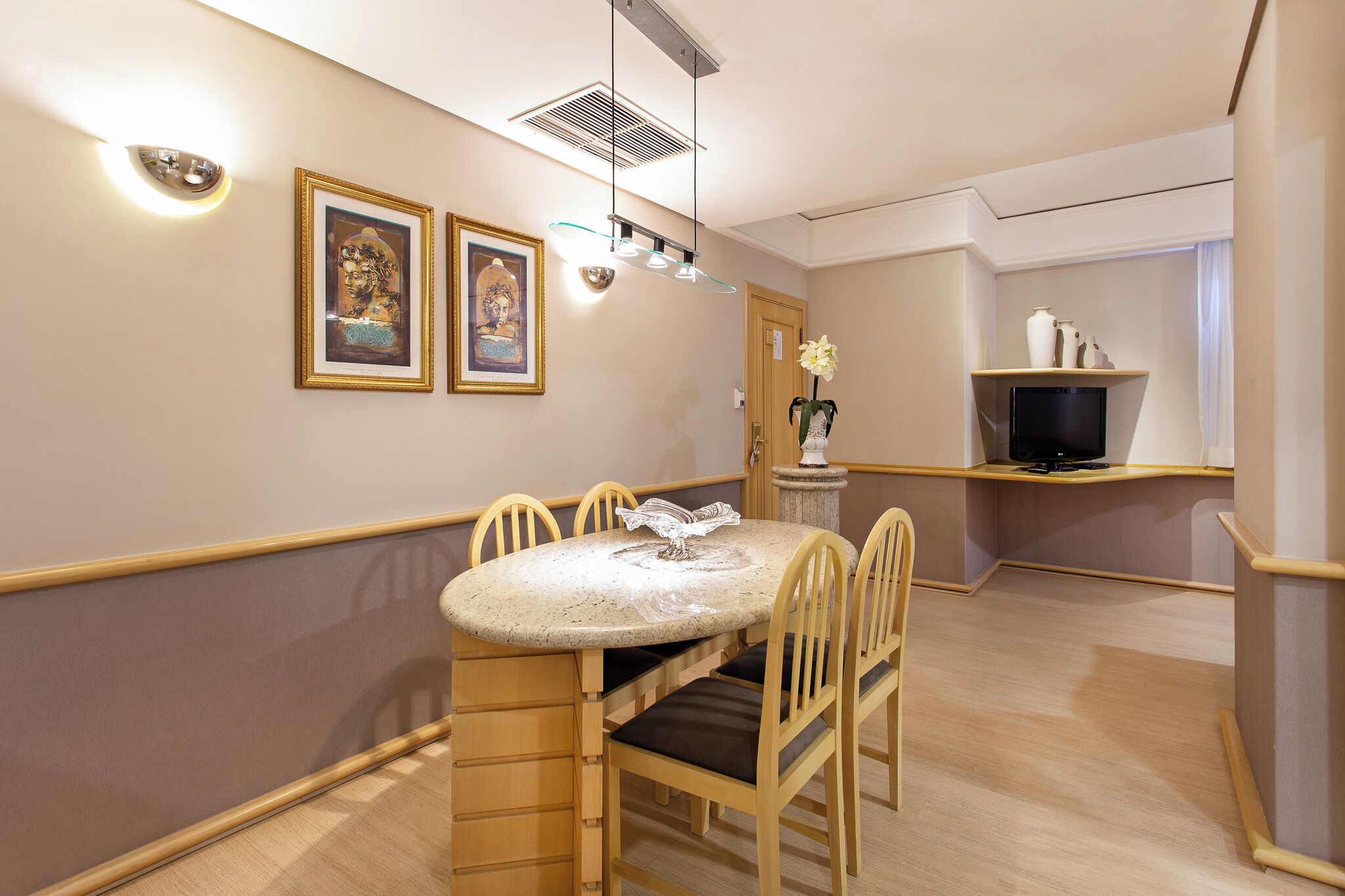 A dining area with a round table, chairs, and wall-mounted light fixtures.