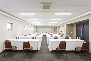 Un salón de conferencias con varias mesas, sillas y piso alfombrado.