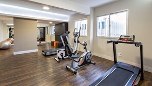 Un gimnasio en casa con equipo de ejercicio, incluyendo cinta de correr, elíptica y bicicleta estática.