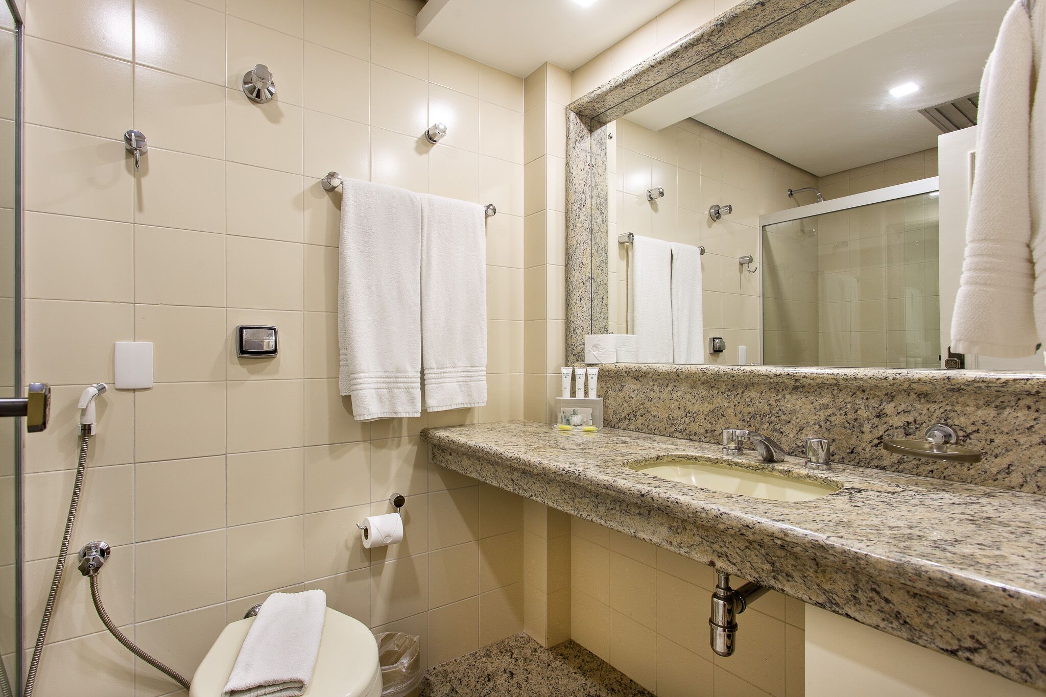 Un baño con lavamanos, espejo, toallero, inodoro y ducha.