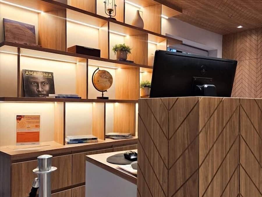 A modern reception desk with a computer, a globe, and a plant on shelves.