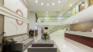 Un vestíbulo amplio con un mostrador de recepción moderno, un espacio de descanso cómodo y una escalera que sube a un nivel superior.