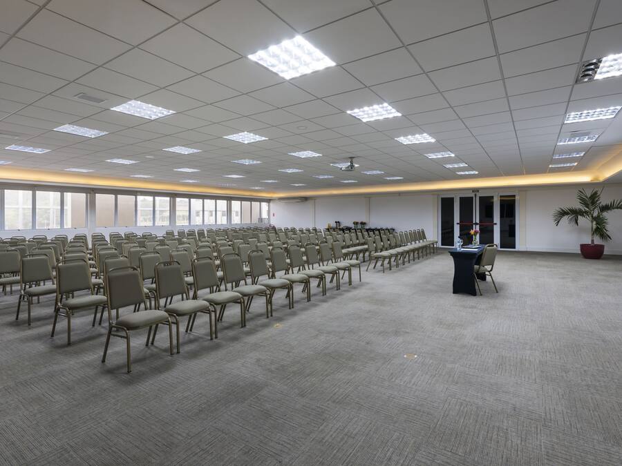 Un salón de conferencias con filas de sillas, un atril y un amplio ventanal.