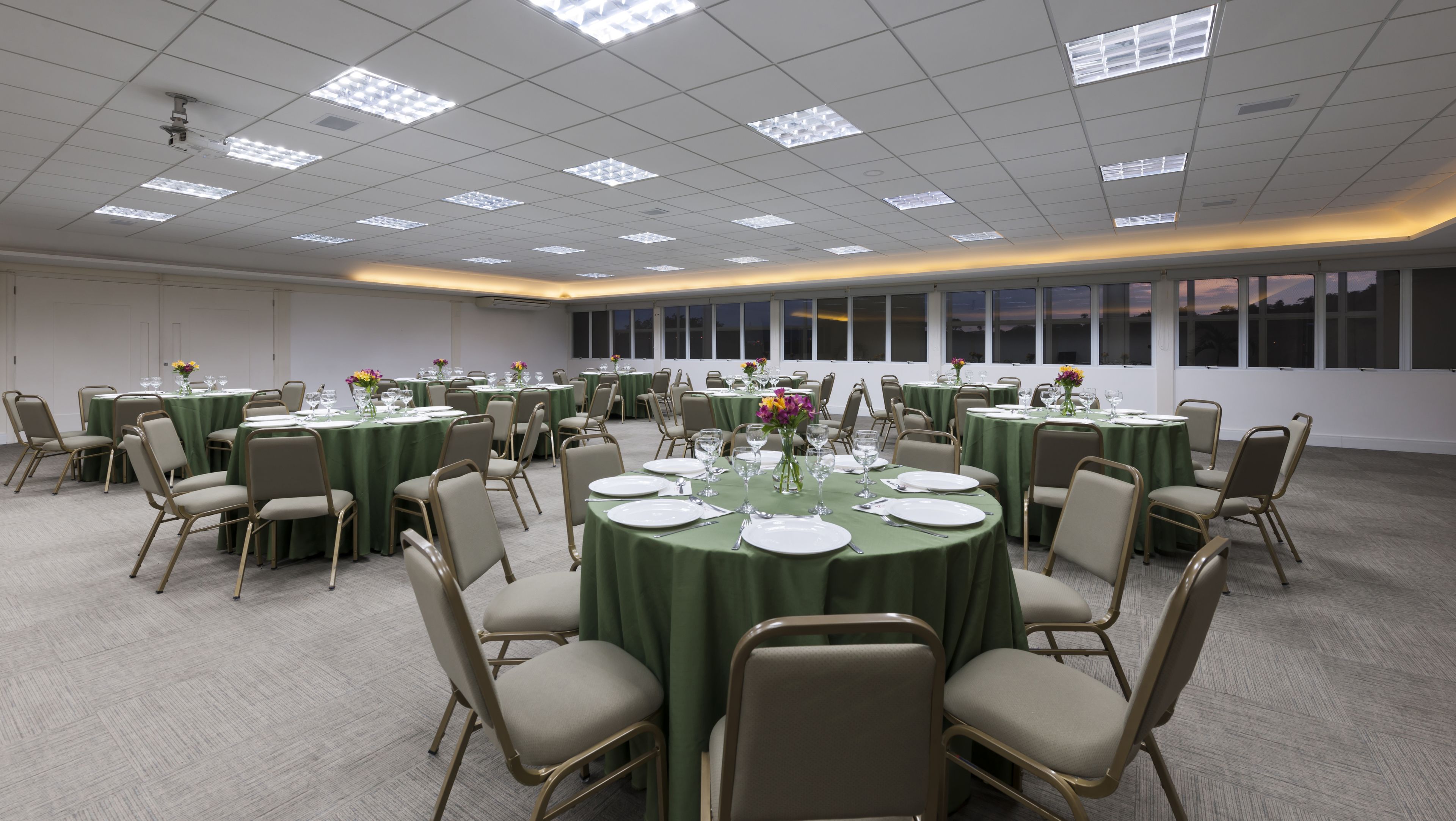 A conference room with round tables, chairs, and floral centerpieces.