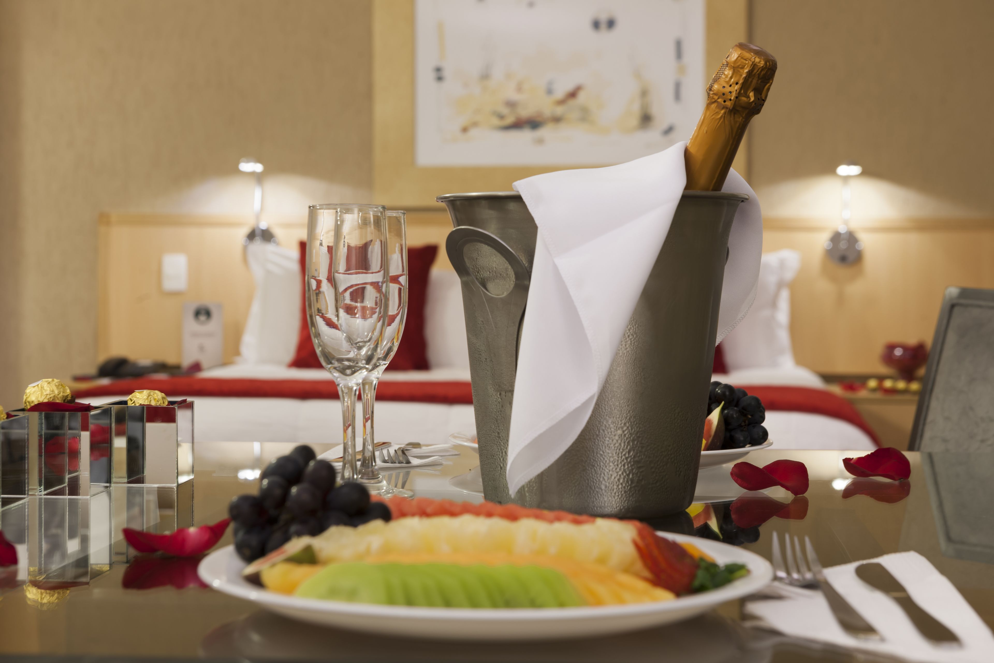 A dining table with a champagne bottle, a glass, and a plate of fruit.