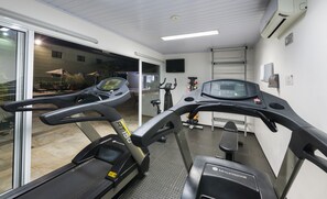 A gym with treadmills, stationary bikes, and a weight bench. - Hotel Matiz Jaguariúna (Jaguariuna)