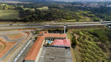 An aerial view of a building with a parking lot, adjacent roads, and surrounding greenery.