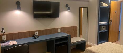Une chambre d’hôtel équipée d’un bureau, d’une chaise, de deux lits, d’une télévision, d’un miroir et d’une armoire.