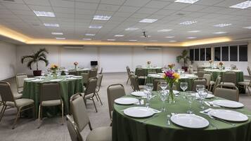 Un salón de conferencias con mesas redondas, sillas y manteles verdes.
