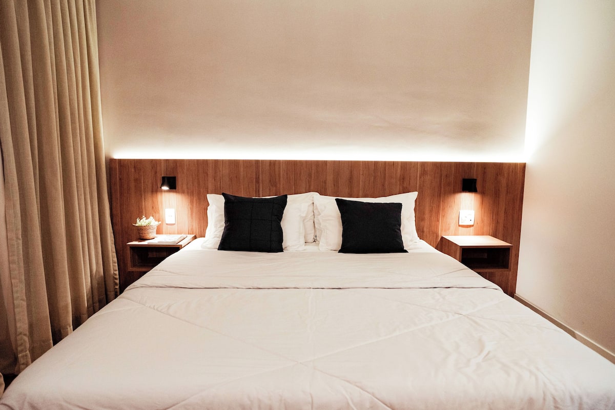 A hotel room with a large bed, two bedside tables with lamps, and a wooden headboard.