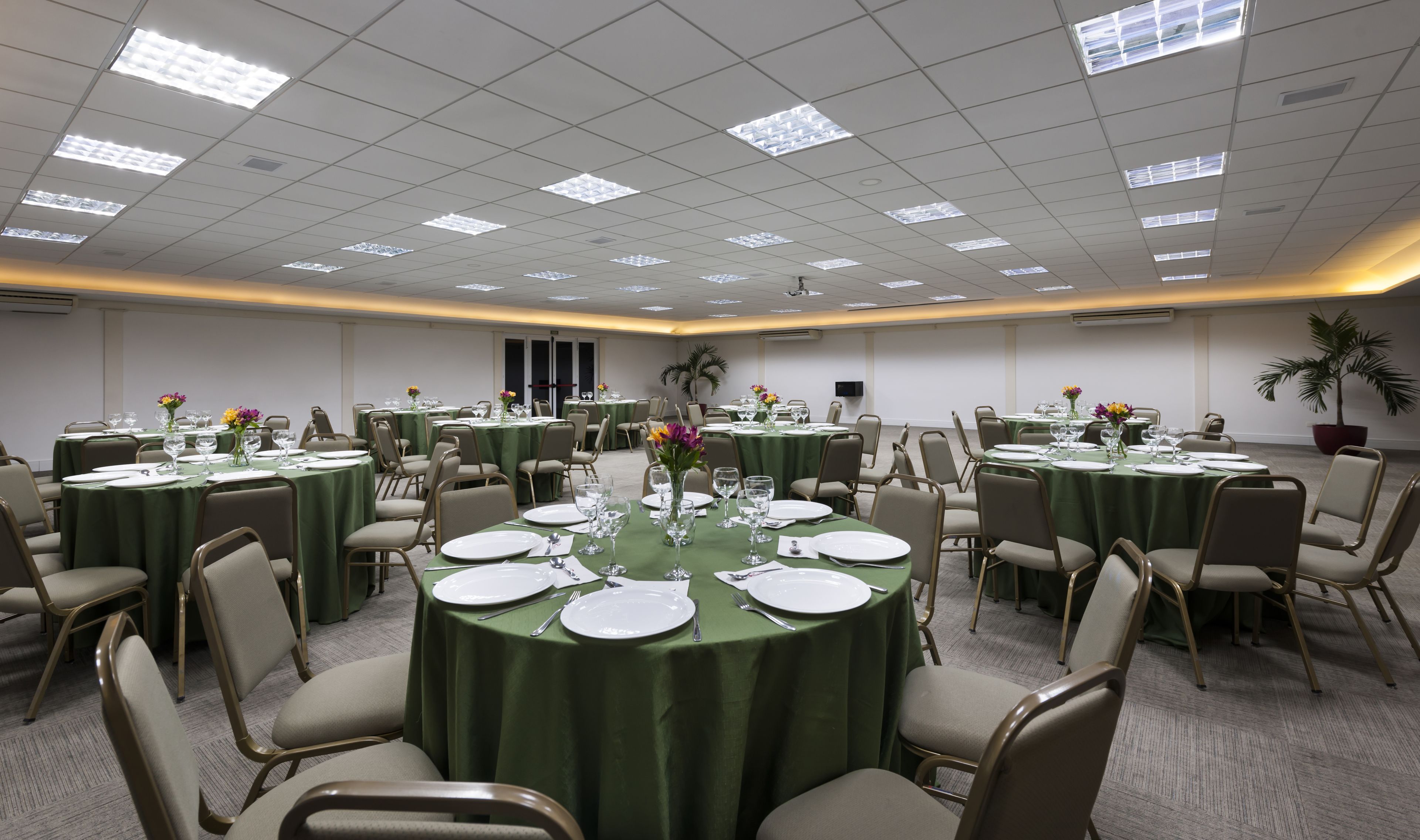 A conference room with round tables, green tablecloths, and beige chairs.