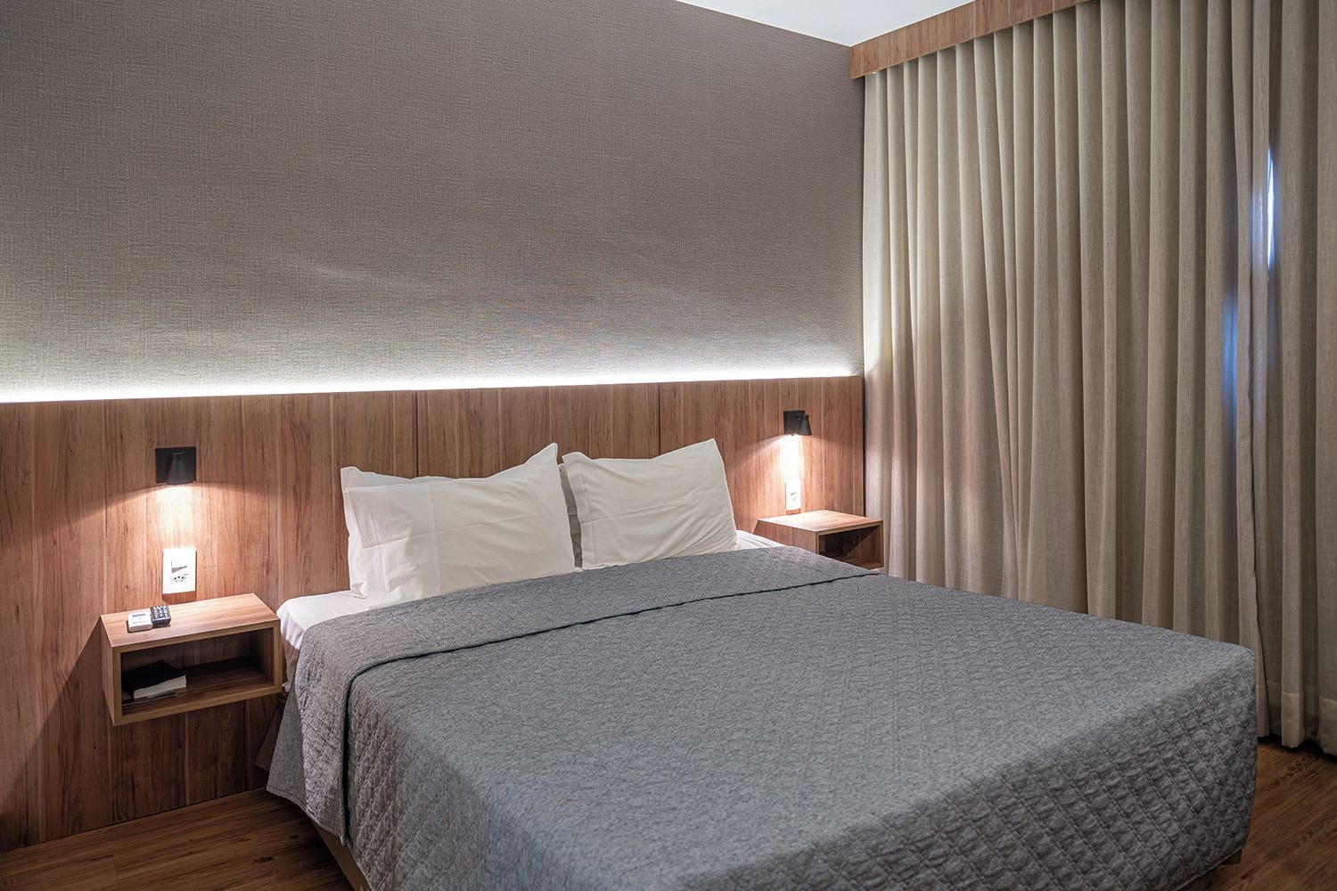 A hotel room with a bed, bedside tables, and a nightstand.