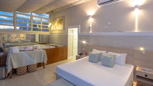 A modern hotel room with a large bed, bedside tables, a bathroom with a bathtub, and a view of the sea through large windows. - Lizon Curitiba Hotel (Curitiba)